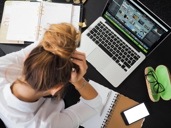 Photo of woman sitting at a desk and struggling with workplace stress.